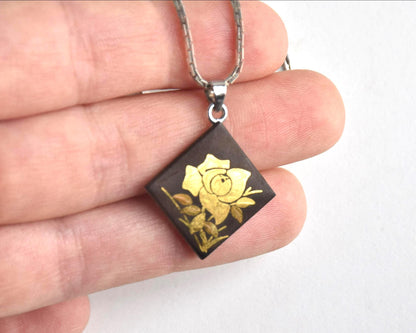 Japanese Zogan Floral Damascene Pendant Necklace held in hand showcasing the square pendant