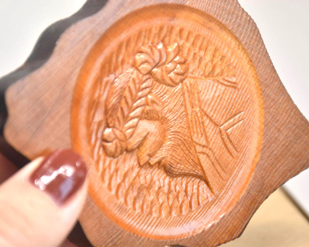 Ainu wooden coaster showing closeup of the carved woman design next to a hand