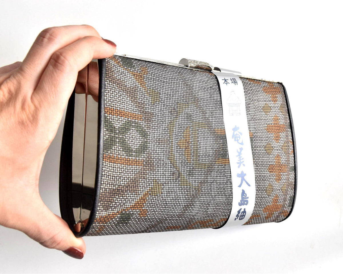 Amami Oshima Tsumugi silk clutch held sideways to show profile size