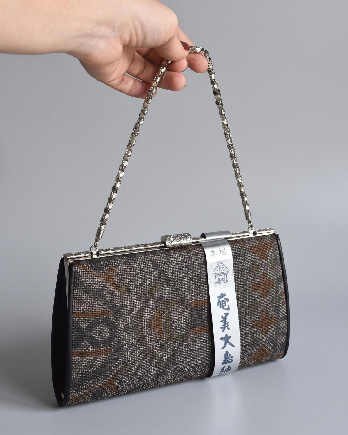 Amami Oshima Tsumugi Silk Clutch Geometric Brown Grey held by chain strap