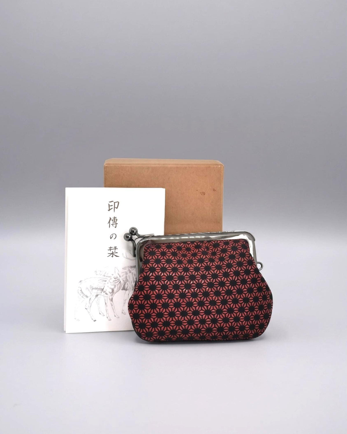 Inden Deerskin Coin Purse With Lacquer Pattern in front of its original box and informational leaflet