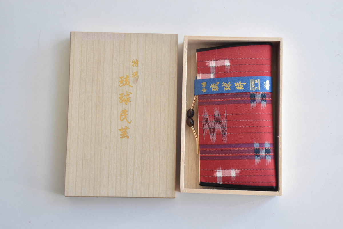 Ryukyu Kasuri Geometric Ikat Silk Wallet Red resting inside its open wooden box