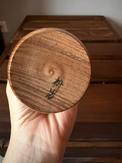Masuo Sato kokeshi doll base held in hand with artist signature visible