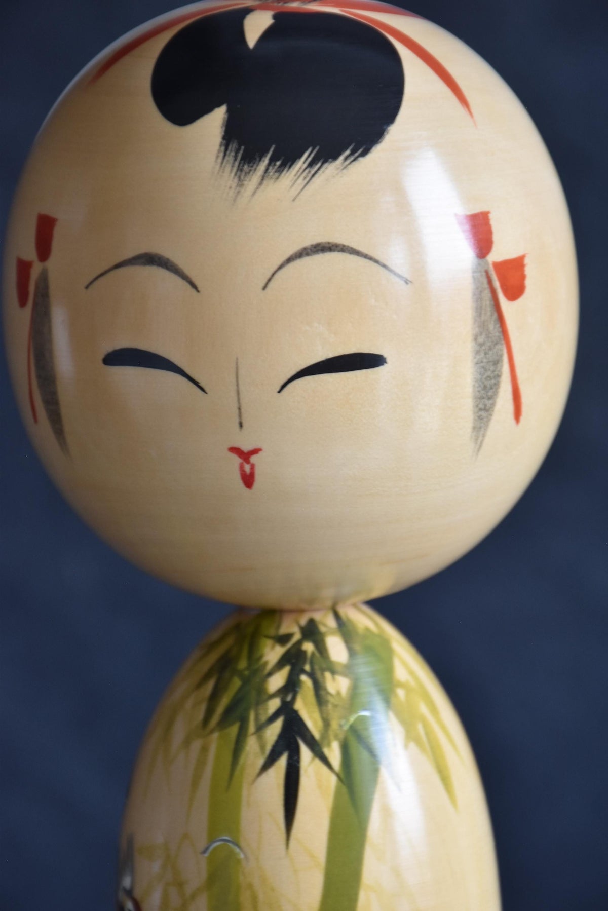 Japanese kokeshi dolls bamboo and floral motif head close-up featuring painted face and hair ribbons