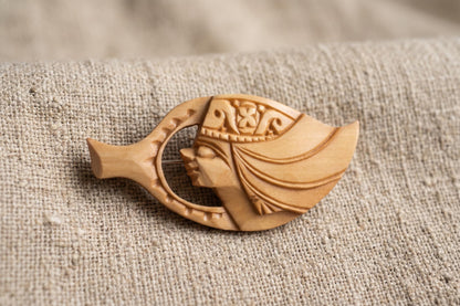 Ainu hand-carved wooden brooch resting on coarse neutral fabric