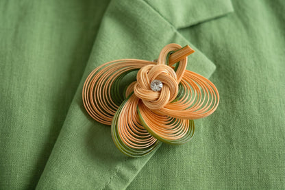 Hand-Woven Bamboo Knot Brooch In Beige And Green styled on a green jacket