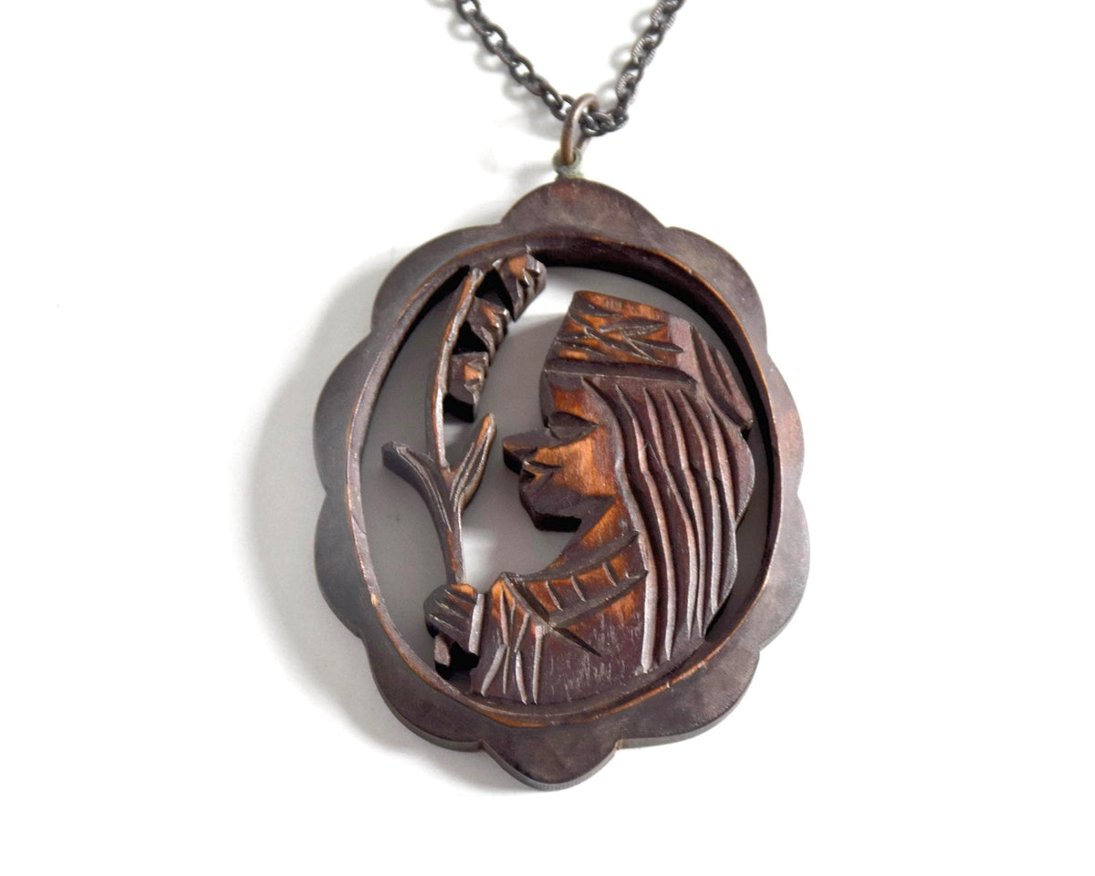 Ainu wooden pendant necklace close up of the handcarved figure holding a plant