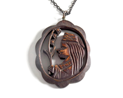 Ainu wooden pendant necklace close up of the handcarved figure holding a plant