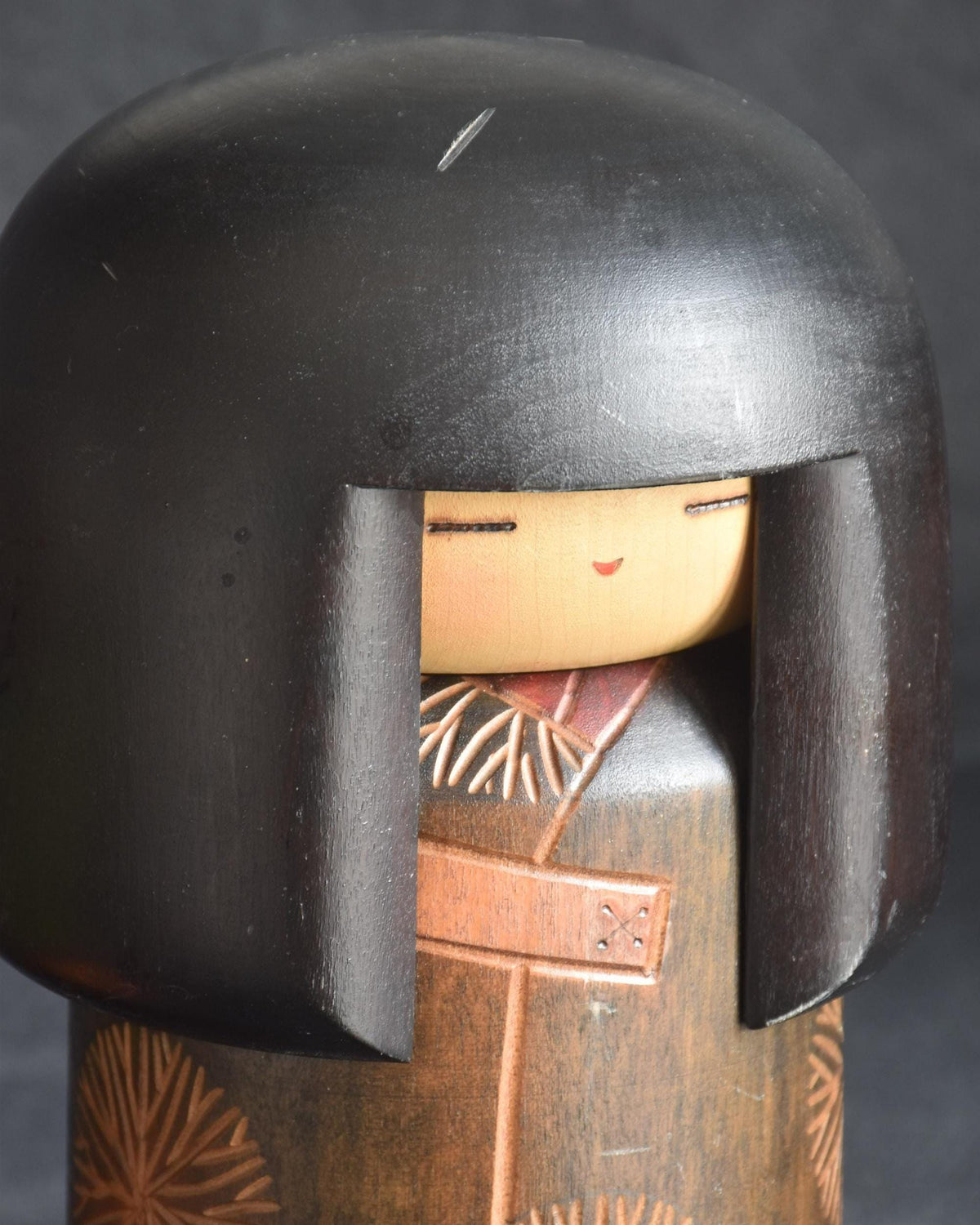 Sansaku Sekiguchi sosaku kokeshi doll, close up of the face and carved wooden kimono