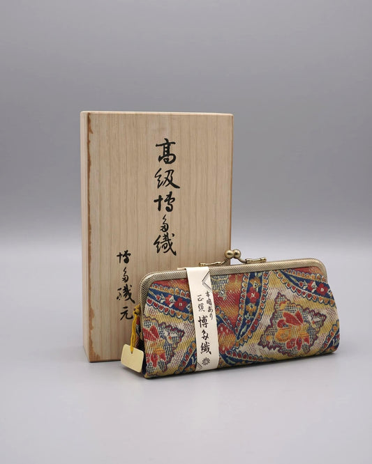 Hakata-Ori Silk Floral Clasp Purse resting vertically beside its inscribed wooden storage box.