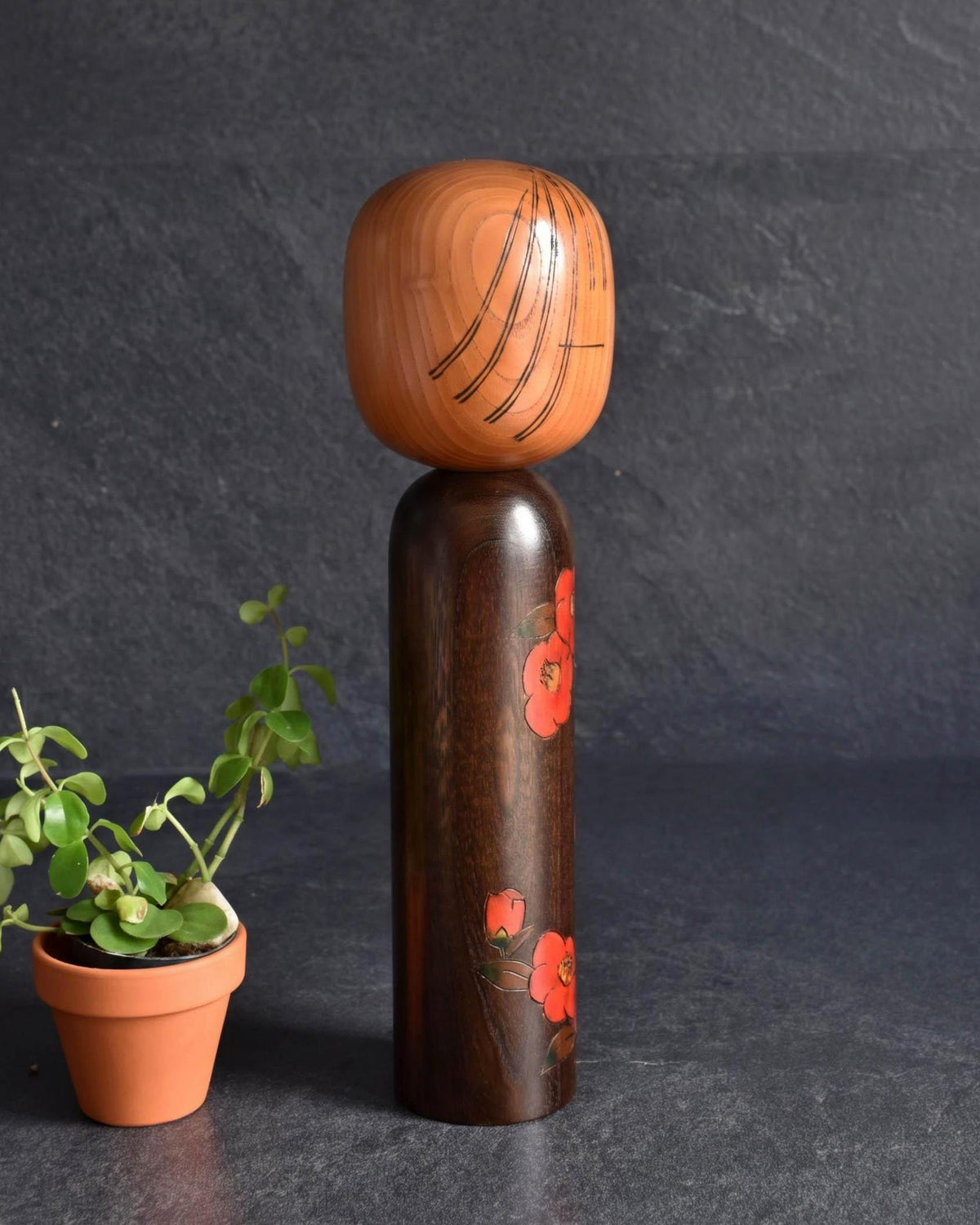 Ryozo Tsujita kokeshi doll angled view showing painted red camellia flowers and minimalist face
