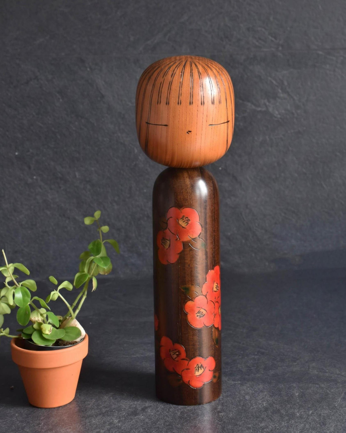 Tsujita Ryozo Sosaku Kokeshi Red Camellia Wood Doll featuring red camellia blossoms on a slender dark body