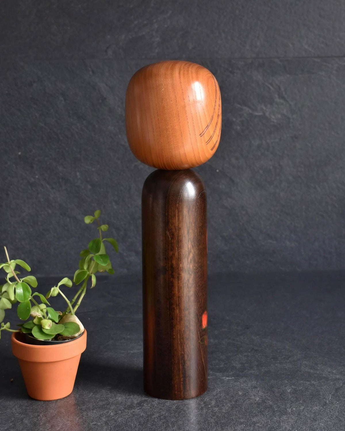 Ryozo Tsujita kokeshi doll side view showing the dark stained body and natural wood head