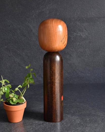 Ryozo Tsujita kokeshi doll side view showing the dark stained body and natural wood head
