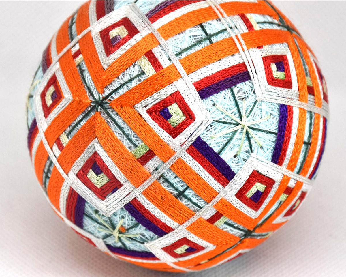 Japanese Temari ball close up of the folk art fabric ball showing multi colored geometric needlework